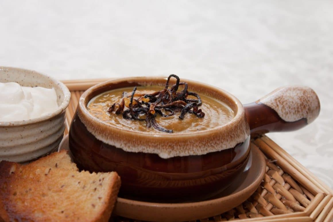 o porție de supă cremă de dovleac plăcintar cu ceapă caramelizată deaspura și o felie de pâine prăjită. Rețete cu dovleac