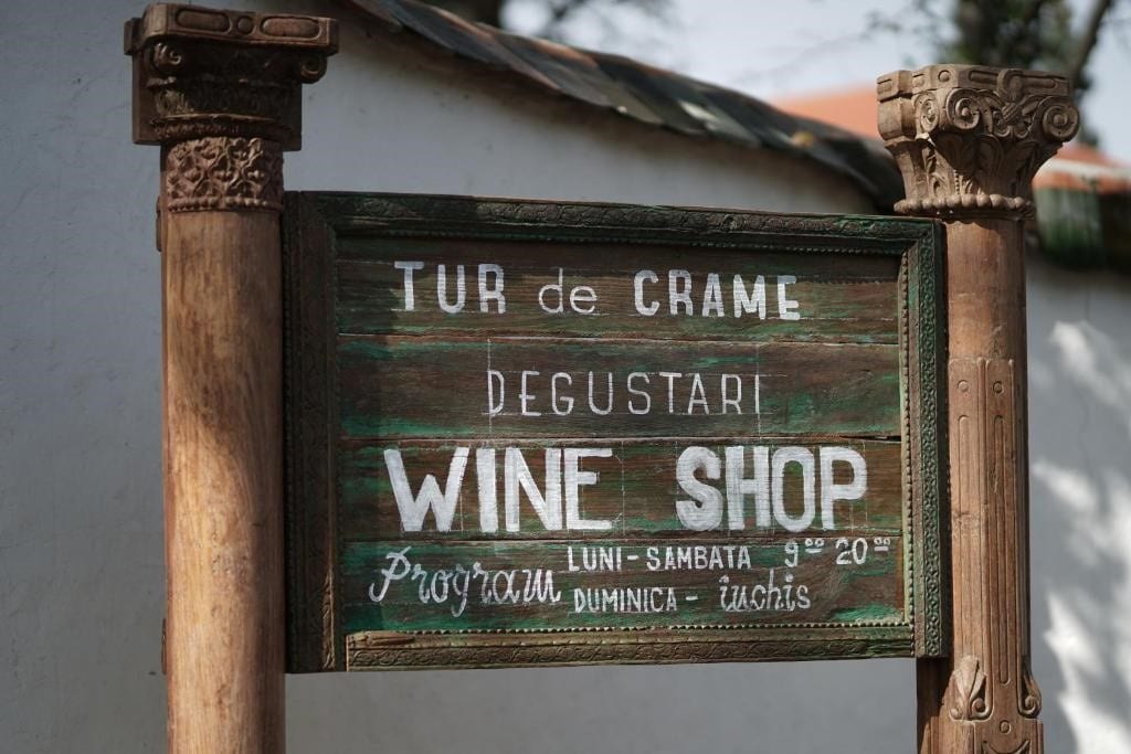 un semn de lemn de la intrarea in crama tohani, intre două coloane romane