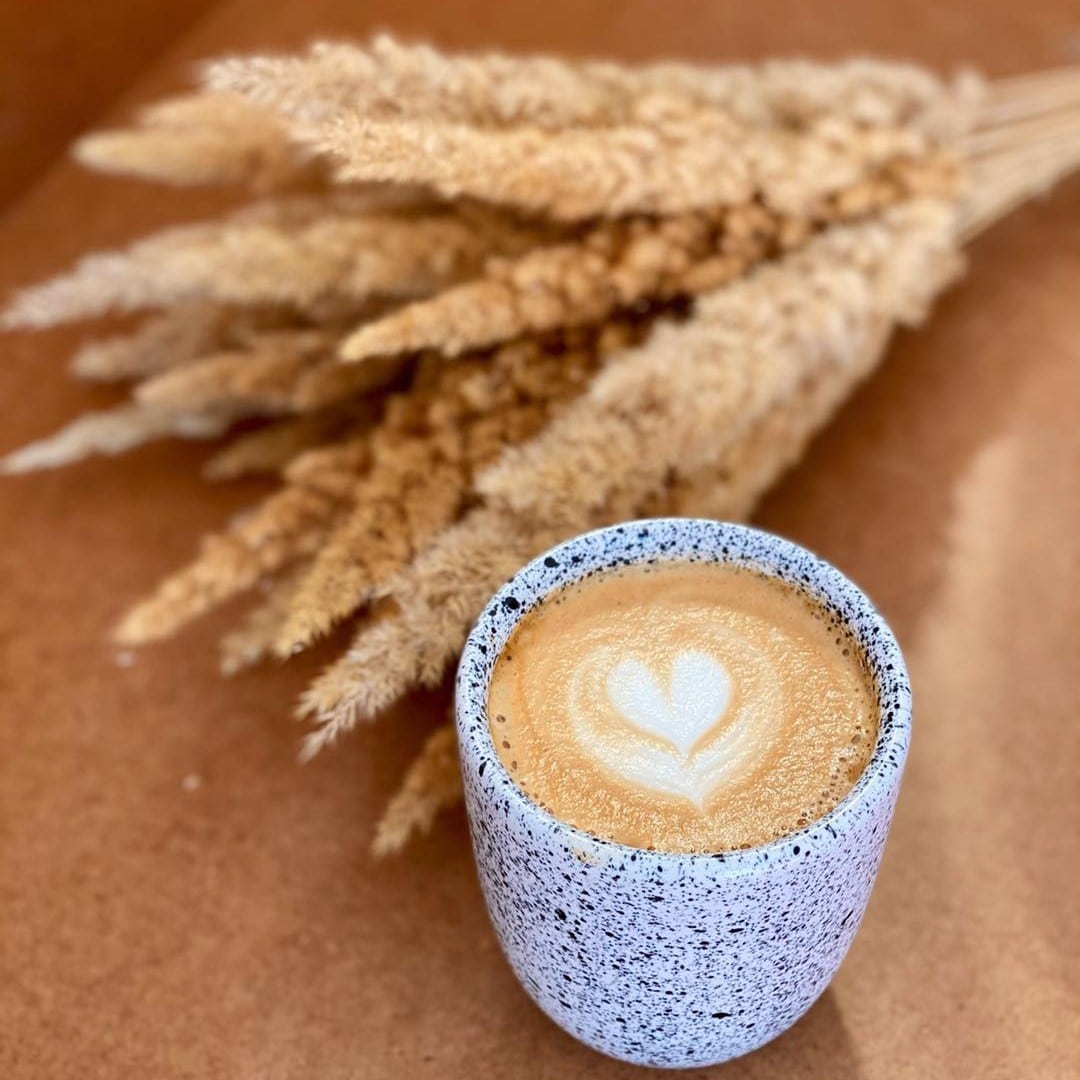 un spic de iarbă uscată este asezat lângp o ceqască de cafea