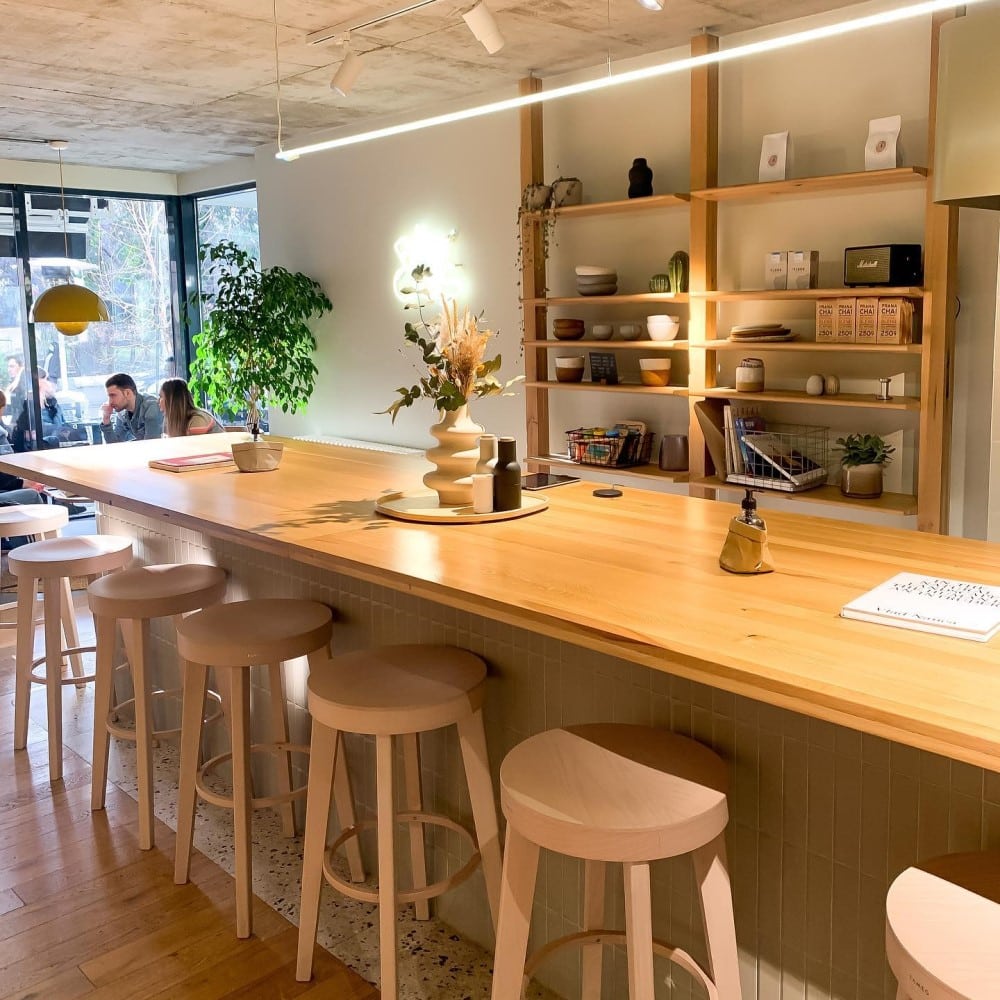 interiorul unei cafenele micute din bucuresti, cu multe plante verzi și mobilier din lemn