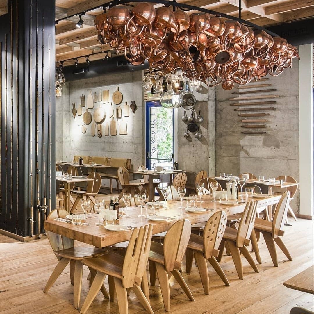 masa lunga de lemn cu un candelabru din oale din alamă deasupra, la restaurant Sardin