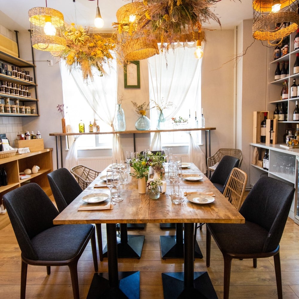 masa de 8 persoane, in dreptul unor geamuri mari, cu rafturi cu vin de-o parte si de alta, la Bacania Veche Bucuresti