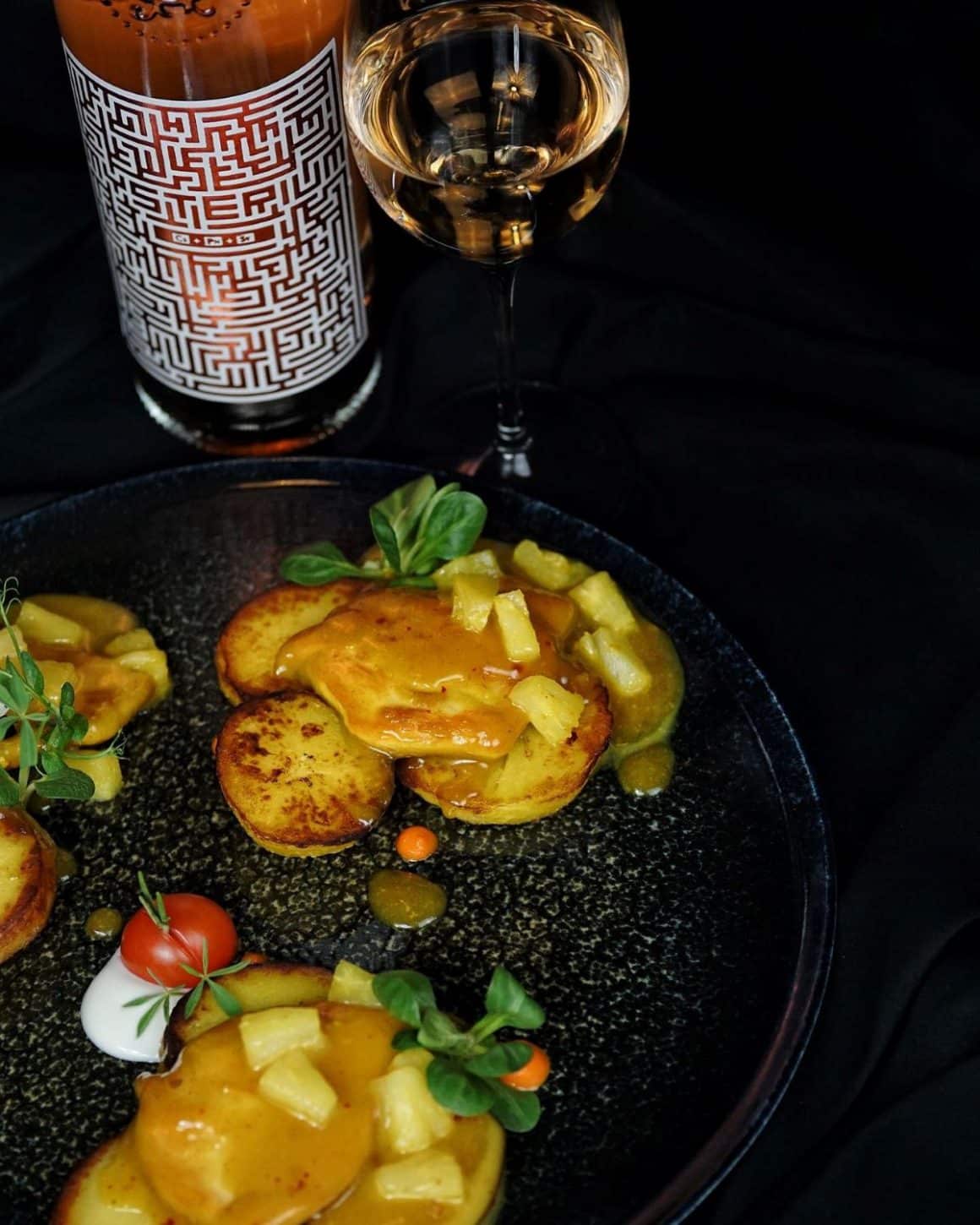 o porție de mâncare cu sos și micro-planteeste servită pe o farfurie neagră, într-un restaurant din alba iulia