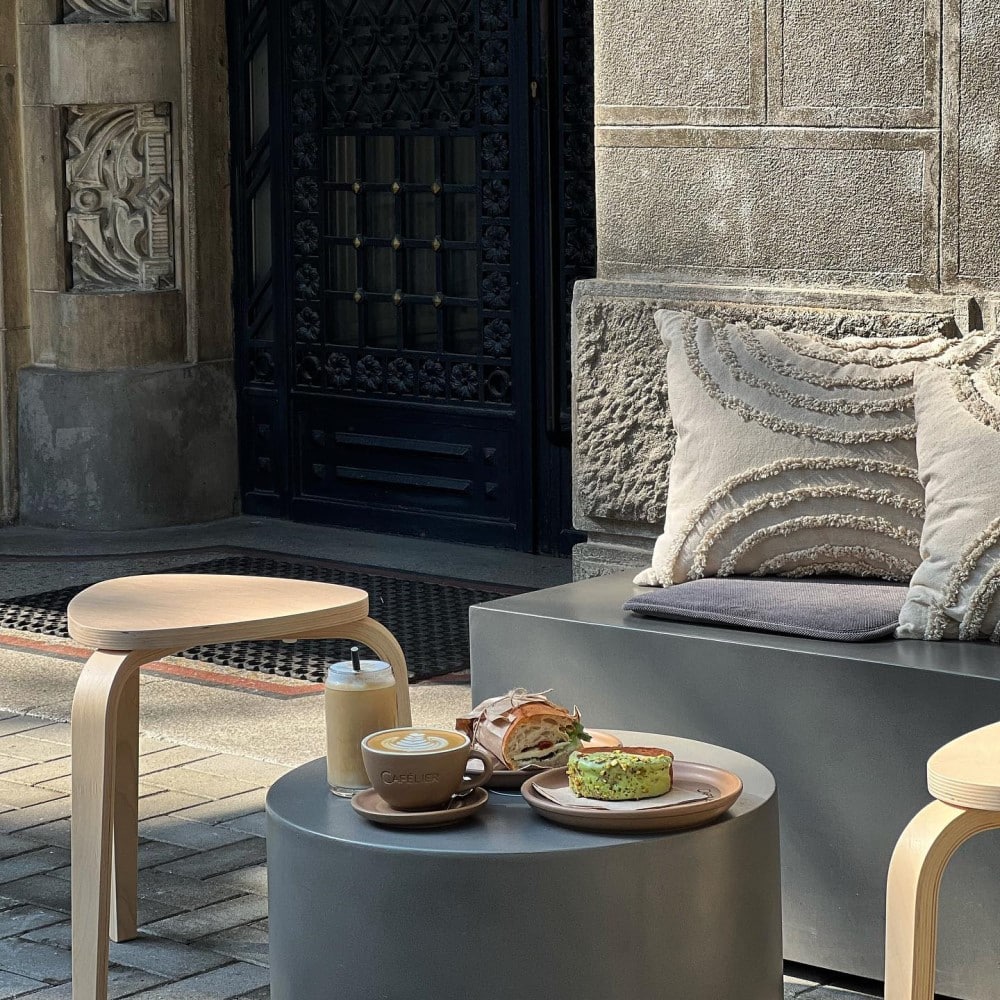 mobilierul exterior al unei cafenele din bucuresti, cu un scaun de lemn, o măsuță și o banchetă