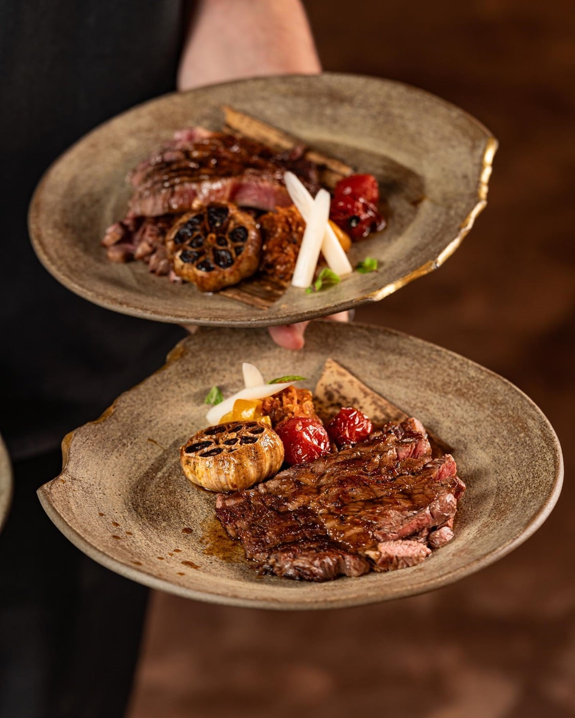 close up cu mana unui ospatar care tine 2 farfurii cu fritprua si usturoi copt, la Yoshi Sushi - restaurante japoneze din București