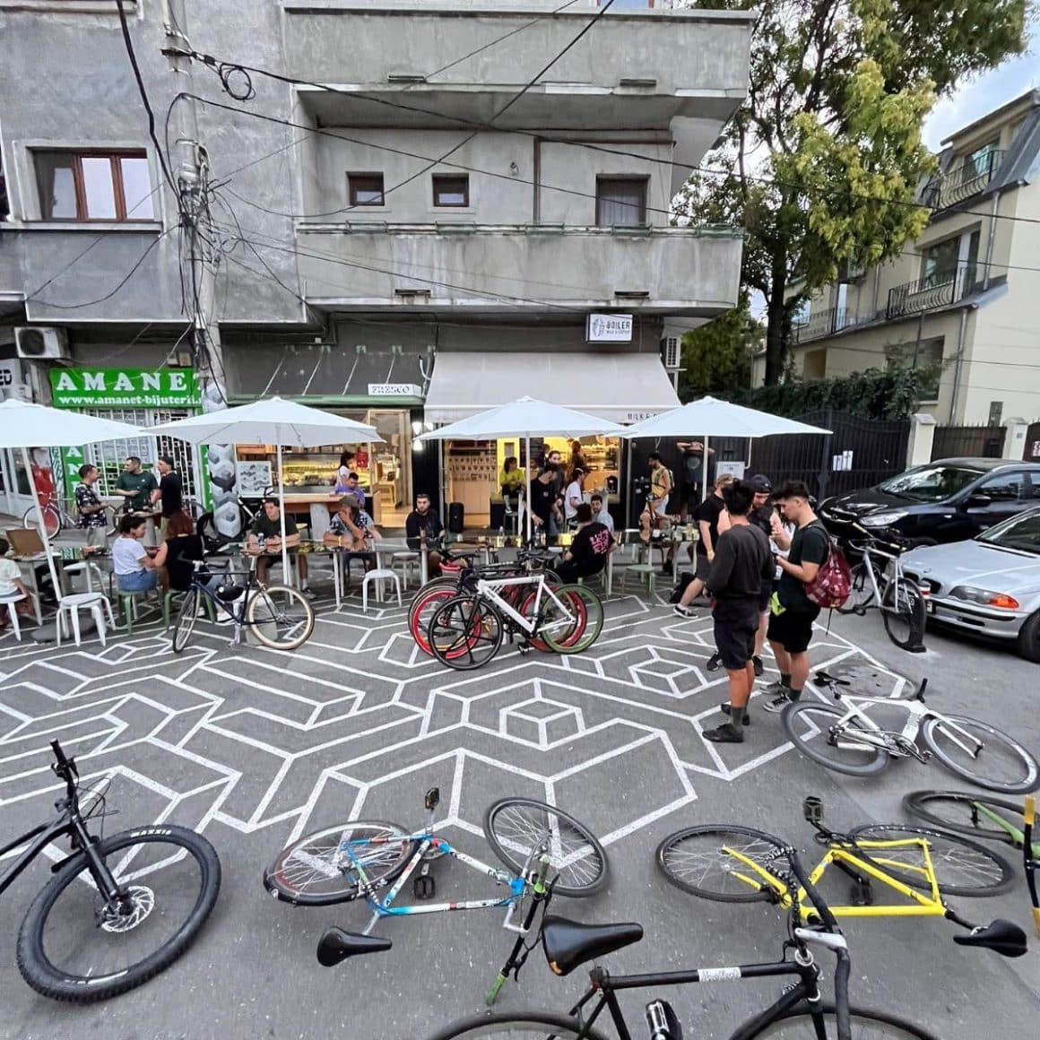 mai multi tineri socializează în fata unei cafenele micute din bucuresti