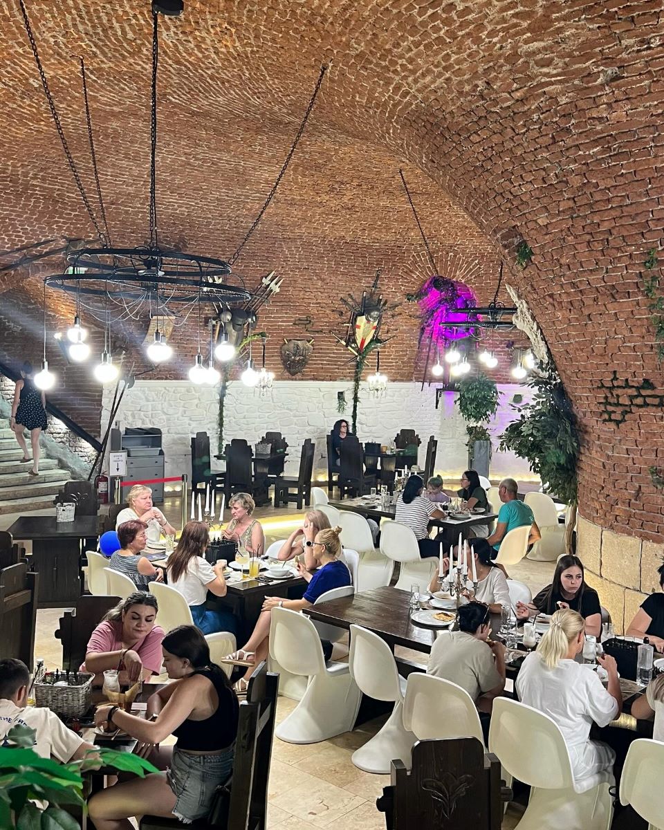 mai multți oameni iau masa intrun restaurant din alba iulia, cu pereți rotunzi de cărămidă