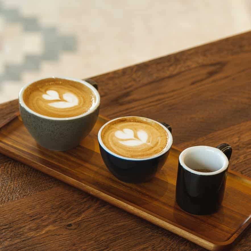 3 cesti de cafea de dimensiuni diferite, pe un platou de lemn la Gyst, unul din localuri cu aer scandinav din București