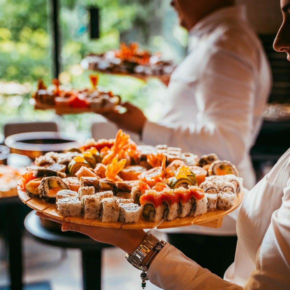 ospatari servesc platouri cu sushi