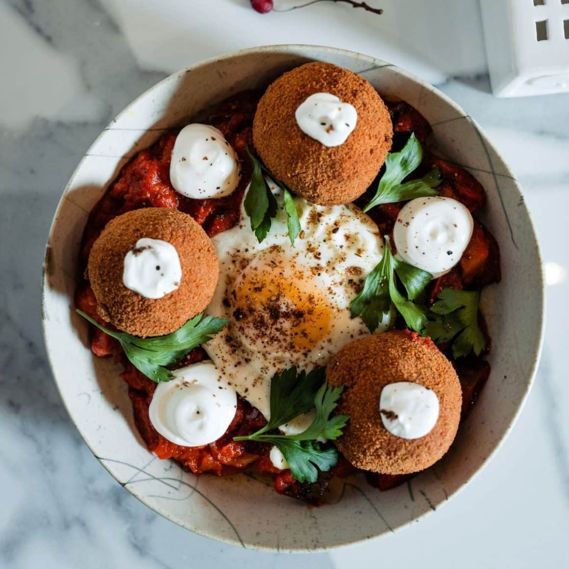 o portie de mancare cu frunze verzi, trei găluște  și un ou ochi