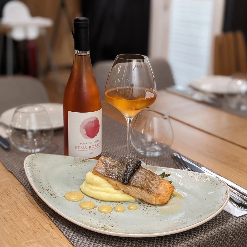 farfurie cu peste si piure alaturi de o sticla si un pahar de vin roze la Sardin