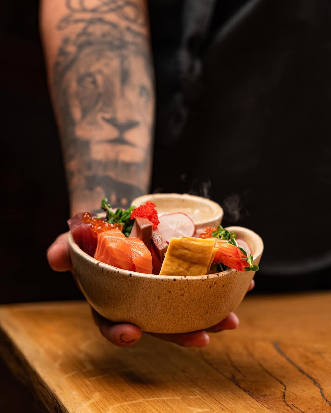 close up cu mana unui ospatar care tine un bol plin cu preparate din bucătăria japoneză de la Yoshi Sushi - restaurante japoneze din București