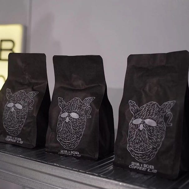 trei pachete de cafea vidate sunt asezate pe un raft