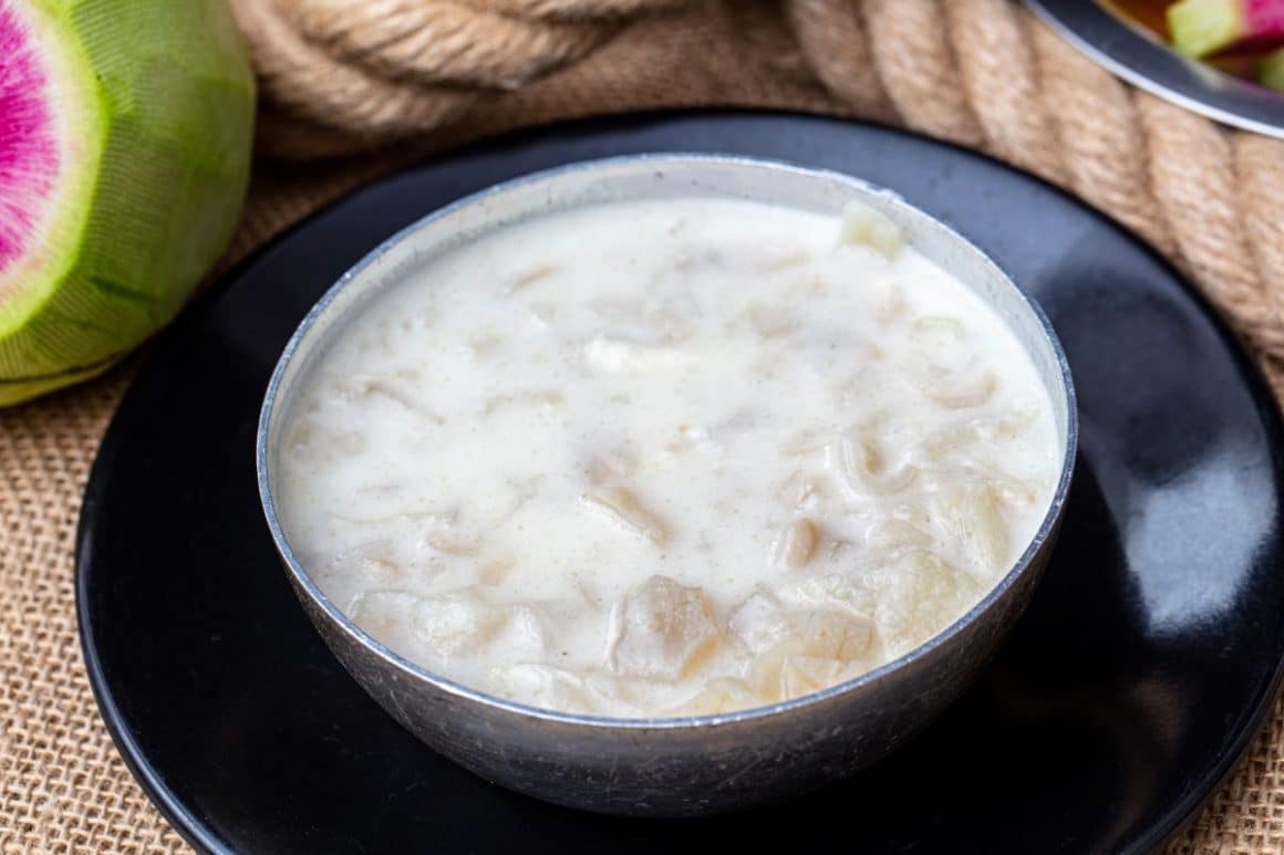 un bol plin cu ciorbă de burtă dreasă cu smântână, asezat pe o farfurie intinsă