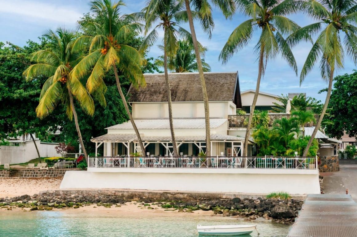 mai multe scaune sunt asezate in jurul unei mese pe terasa unui hotel din mauritius