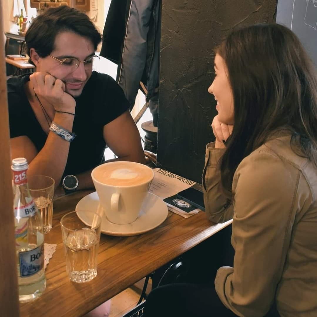 un cuplu imparte o ceasca foaret mare de cappuccino la Camera din fata Bucuresti