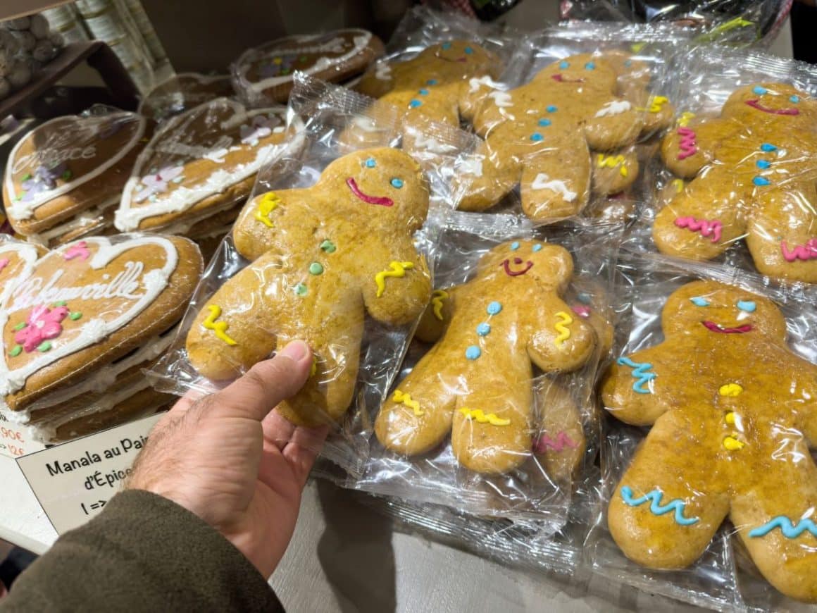 mai multe figurine din turta dulce, mannelle, sunt asezate pe marginea unei tarabe cu dulciuri de la un târg de crăciun din colmar