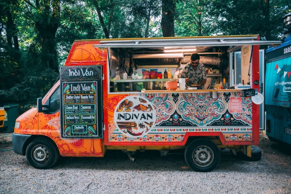 un brabrat prepară o potrie de mancare la un festival gastronomic, într-un food truck