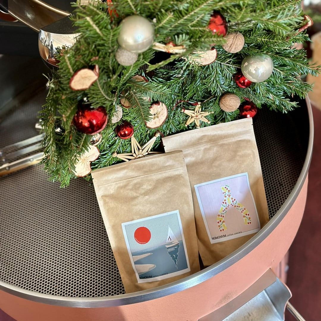 pungute cu cafea prajita, asezata langa un brad impodobit la Nomonym Coffee Roastery București. Unde ieșim în București la băuturi calde, de iarnă.