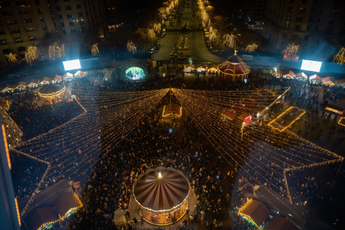 o fotografie aeriană a targului de craciun din piata constituției, cu luminițe și casuțe, unul dintre cele mai frumoase targuri de craciun din romania