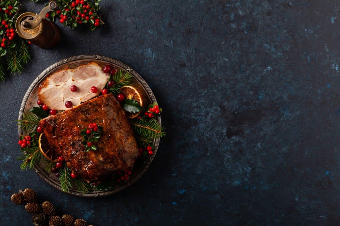 friptură de Crăciun decorată cu crengute de brad, fotografiata de sus, pe fundal negru