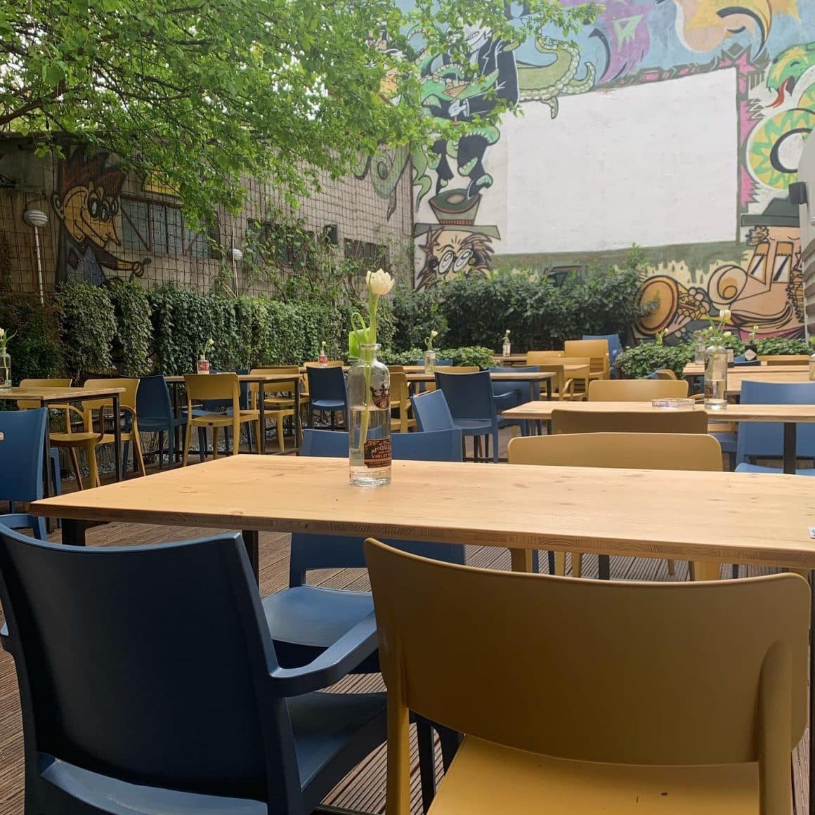 Terasa restaurantului Modelier, cu multe mese si un perete desenat cu grafitti.