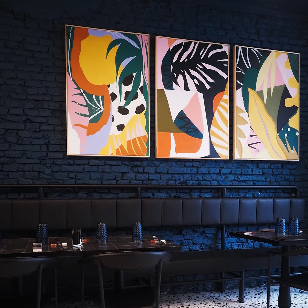 Rualunul din Bistrouri din București, cu mobilier din piele neagra, pereti albastru inchis si tablouri foarte colorate