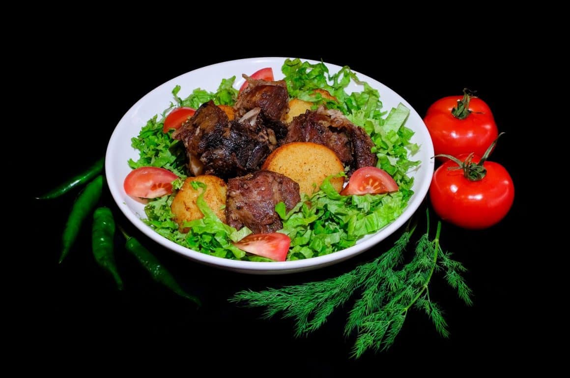 o farfurie albă, rotundă, cu mai multe ingrediente folosite la prepararea unei salate calde salate calde