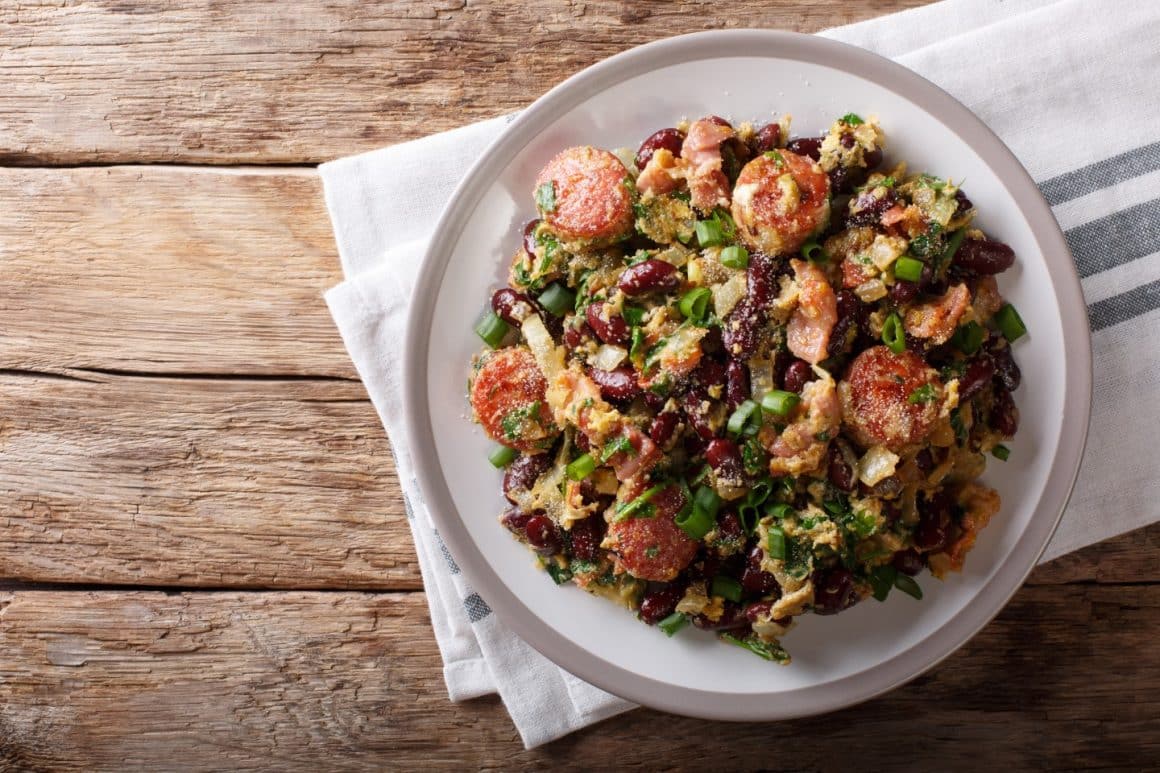 un bol cu mai multe ingrediente folosite la prepararea unei salate calde salate calde, așezat pe un prosop de bucătărie, pe o masă rustică