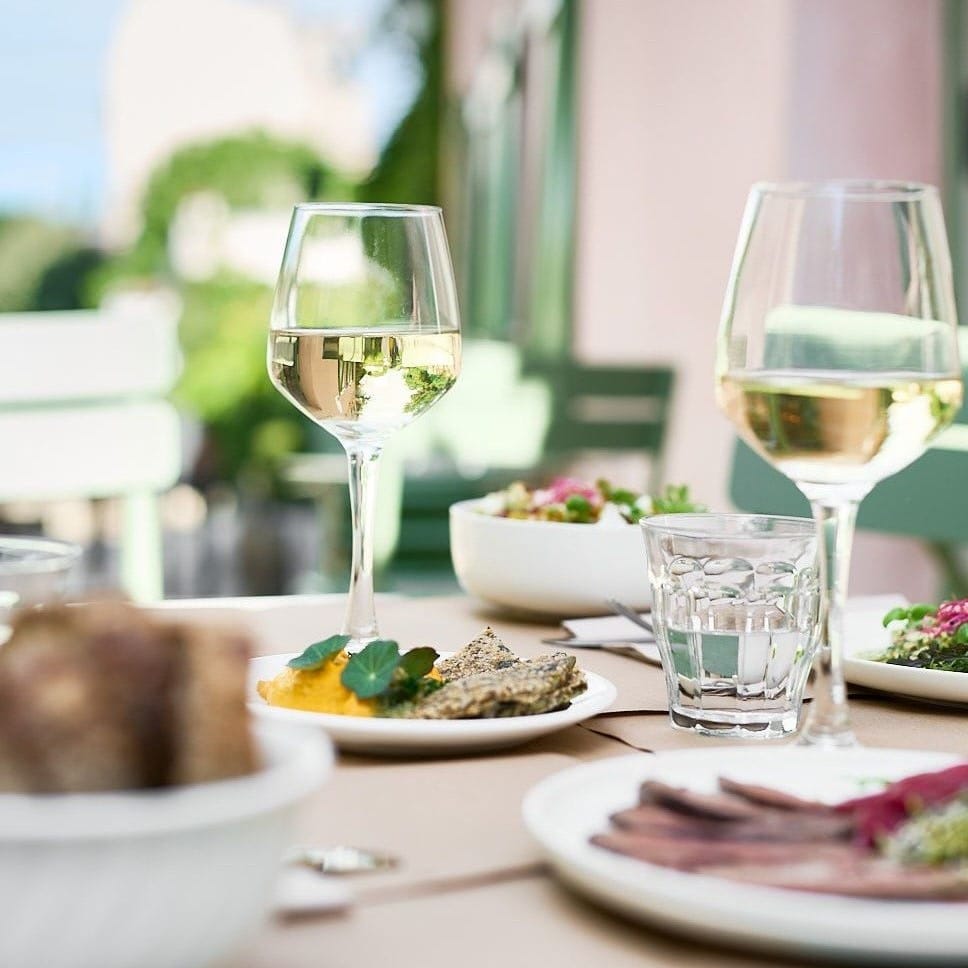 2 pahare de vin si farfurii cu mancare, blurate, la Maison Rose din Paris