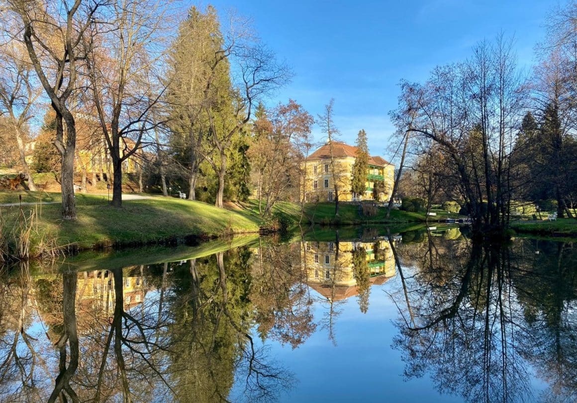 conacul de la Zabola esteta fotografiat din departare, in mijlocul padurii, cu lacul in prim plan. - una din destinații romantice din România