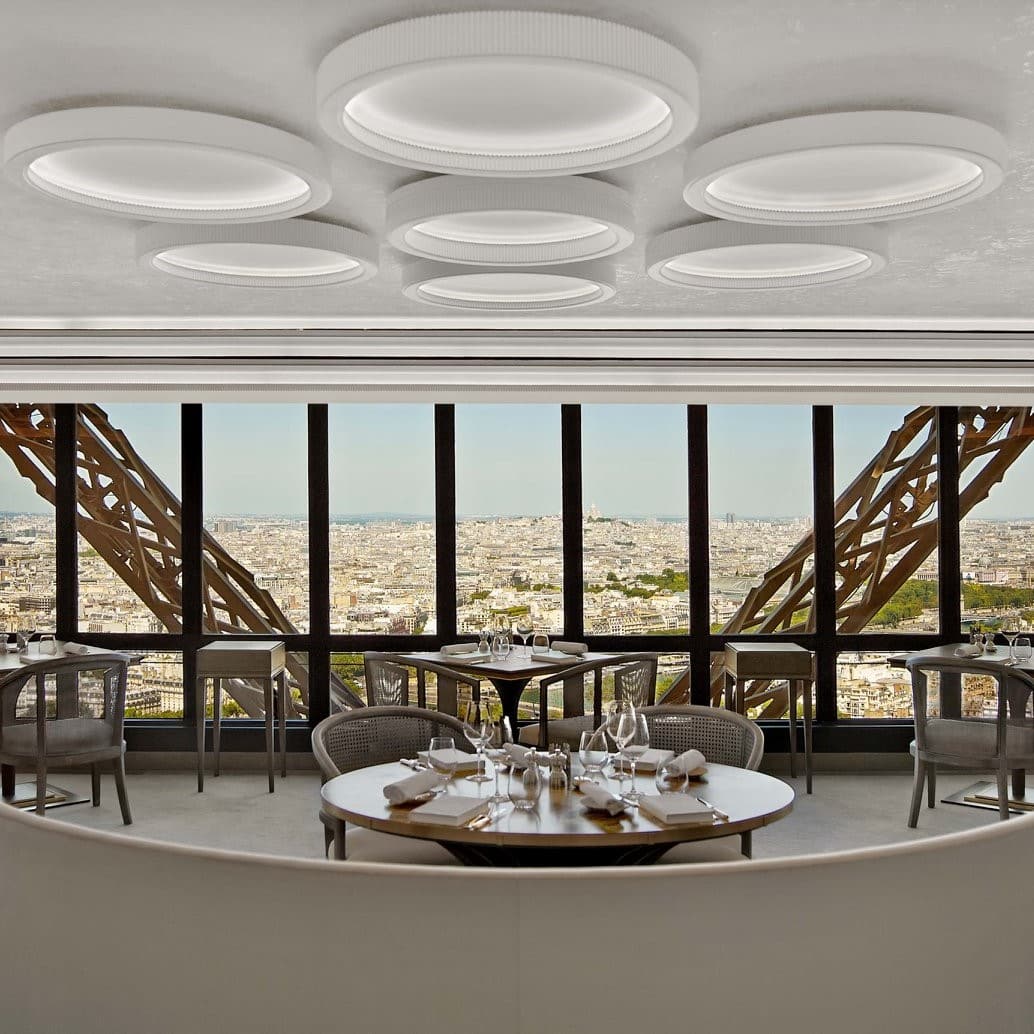 Privire de ansamblu din restaurantul Jules Verne din Turnul Eiffel, decorat elegant, prin ale carui ferestre mari se vede Parisul