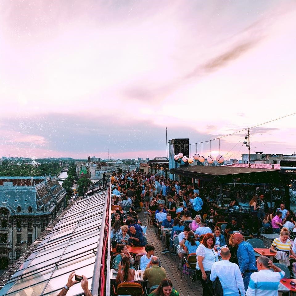 Terasa de la Linea Closer to the Moon, plina de oameni care se distreaza si socializeaza, iar in fundal priveliste panoramica asupra orasului si Cheiul Dambovitei. restaurante la înălțime din București