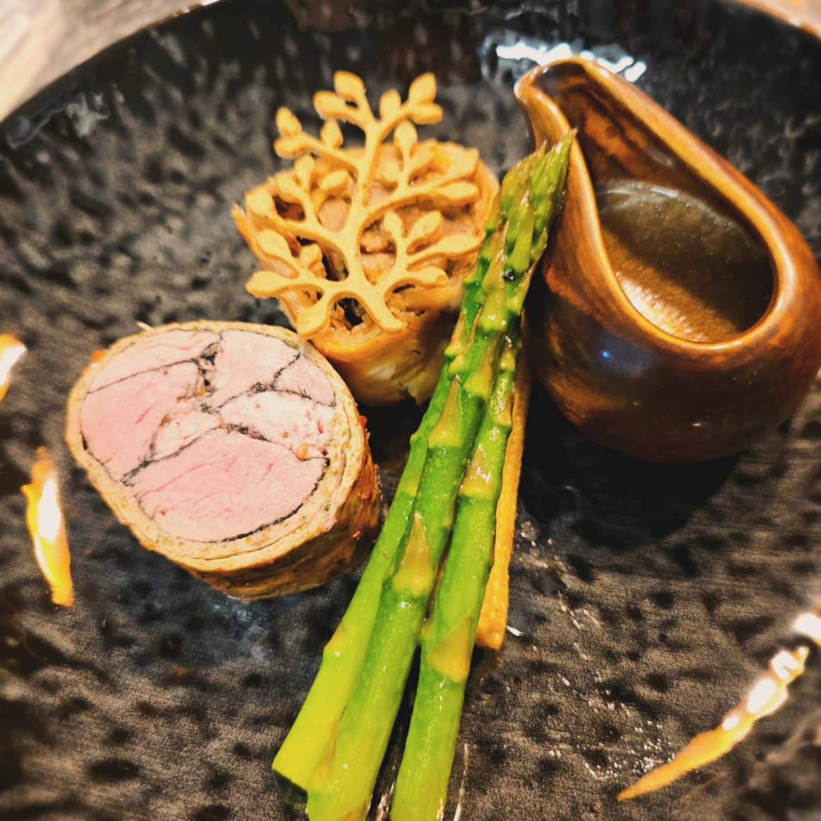 Close up cu o farfurie cu friptura, sparanghel si alte elemente de fine dining la CHef Atelier