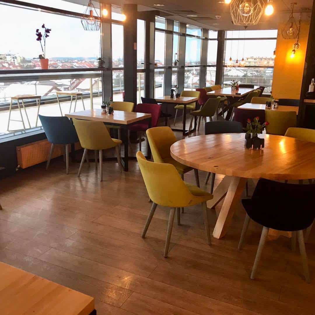mai multe mese si scaune colorate din interiorul restaurantului Elfi Sky Bar