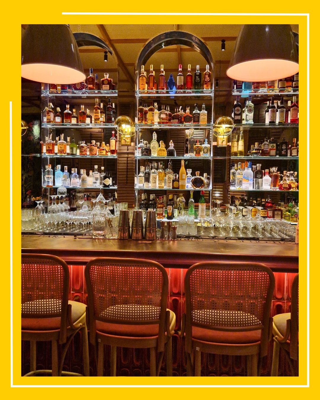 Imagine cu barul de la Condesa, cu scaune inalte in fata si rafturi pline de sticle de bautura