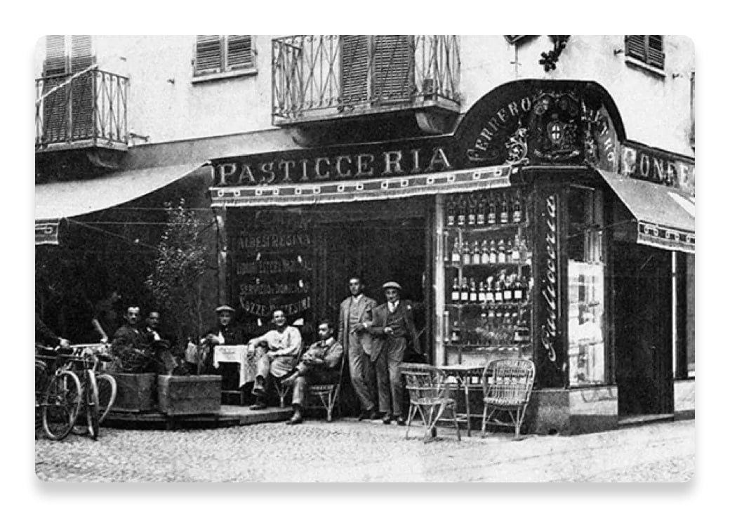 fotografie veche, alb negru, cu mai multi barbati in fata unei pasticcerii din Italia