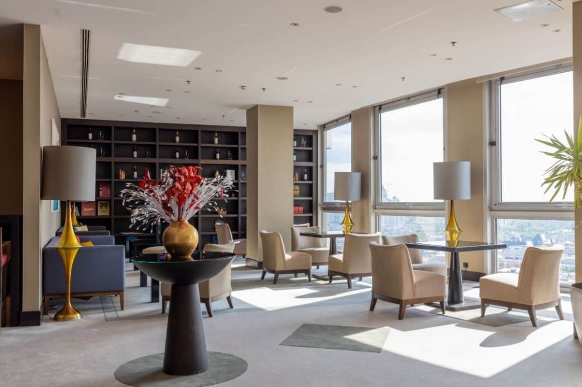 imagine din restaurant Sky Lounge, cu fotolii crem si un perete acoperit de rafturi din lemn wenge. Grand Hotel Bucuresti. estaurante la înălțime din București