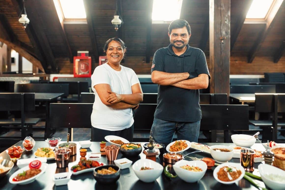 Harry și Arcina, bucatarii de la Mumbai, in fata unei mese pline cu preparatele din restaurant