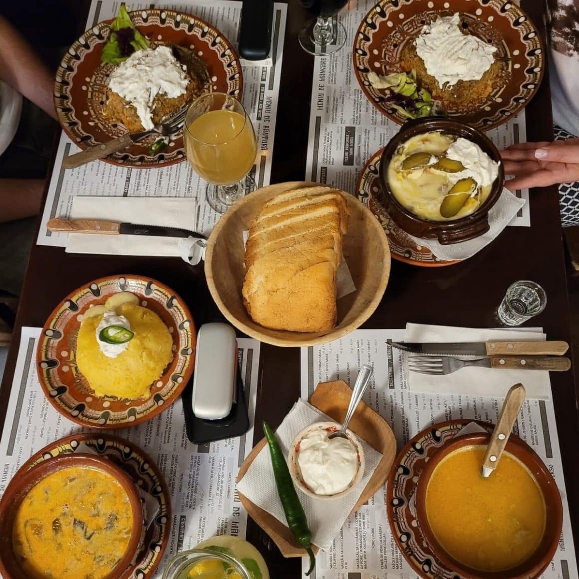 Mai multe farfurii cu ciorba, mamaliga si paine de casa la Restaurant Roata Cluj