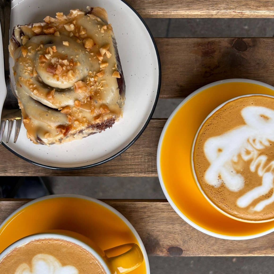 2 cesti d ecafea fotografiata de sus si o farfurie cu melc cu scortisoara