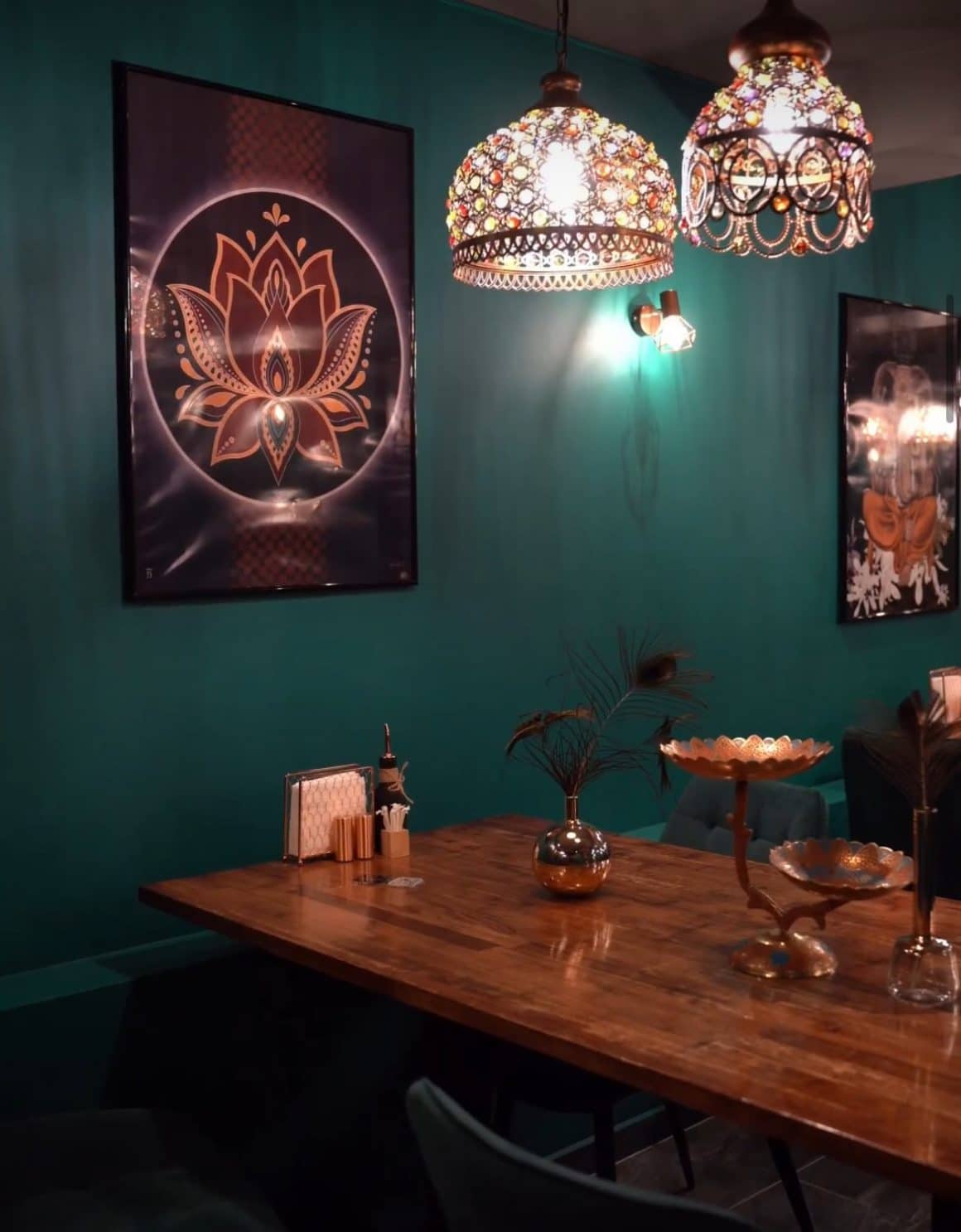 Interiorul restaurantului Mumbai, cu pereti vopsiti verde inchis, mobilier din lemn, candelabre indiene si tablouri indiene. Restaurante etnice cu specific deosebit din București. Restaurant indian