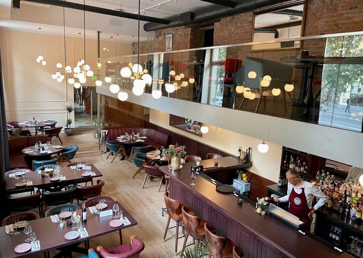 Mai multe mese cu canapele din piele si un ospatar la bar in restaurant Ciao New York din Cluj