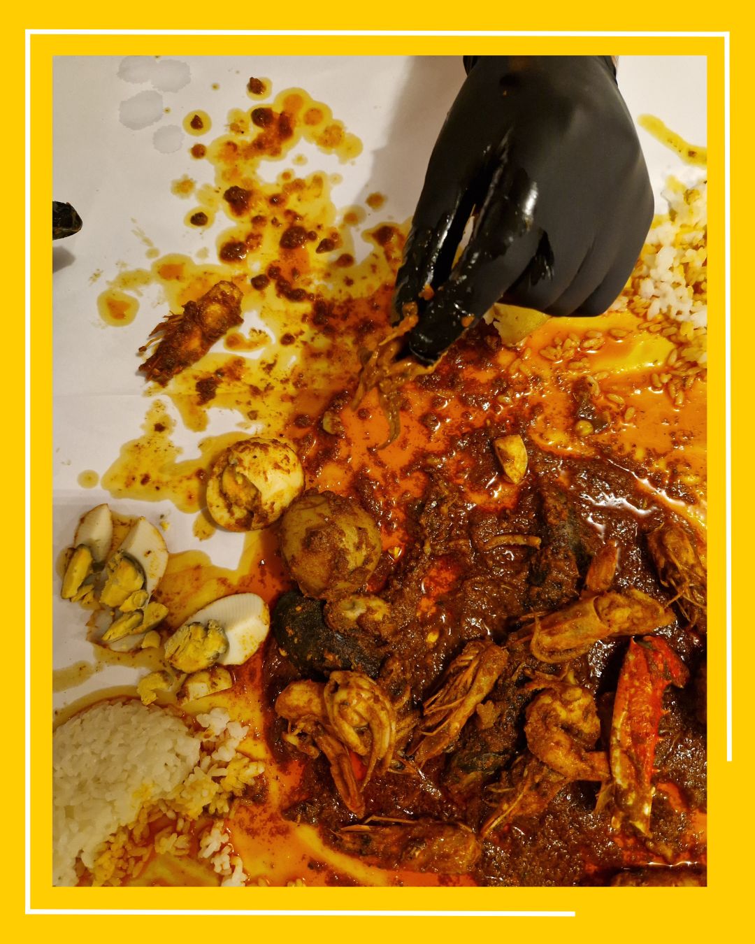 persoana care poarta o manusa neagra mananca cu mana dintr-un platou de fructe de mare