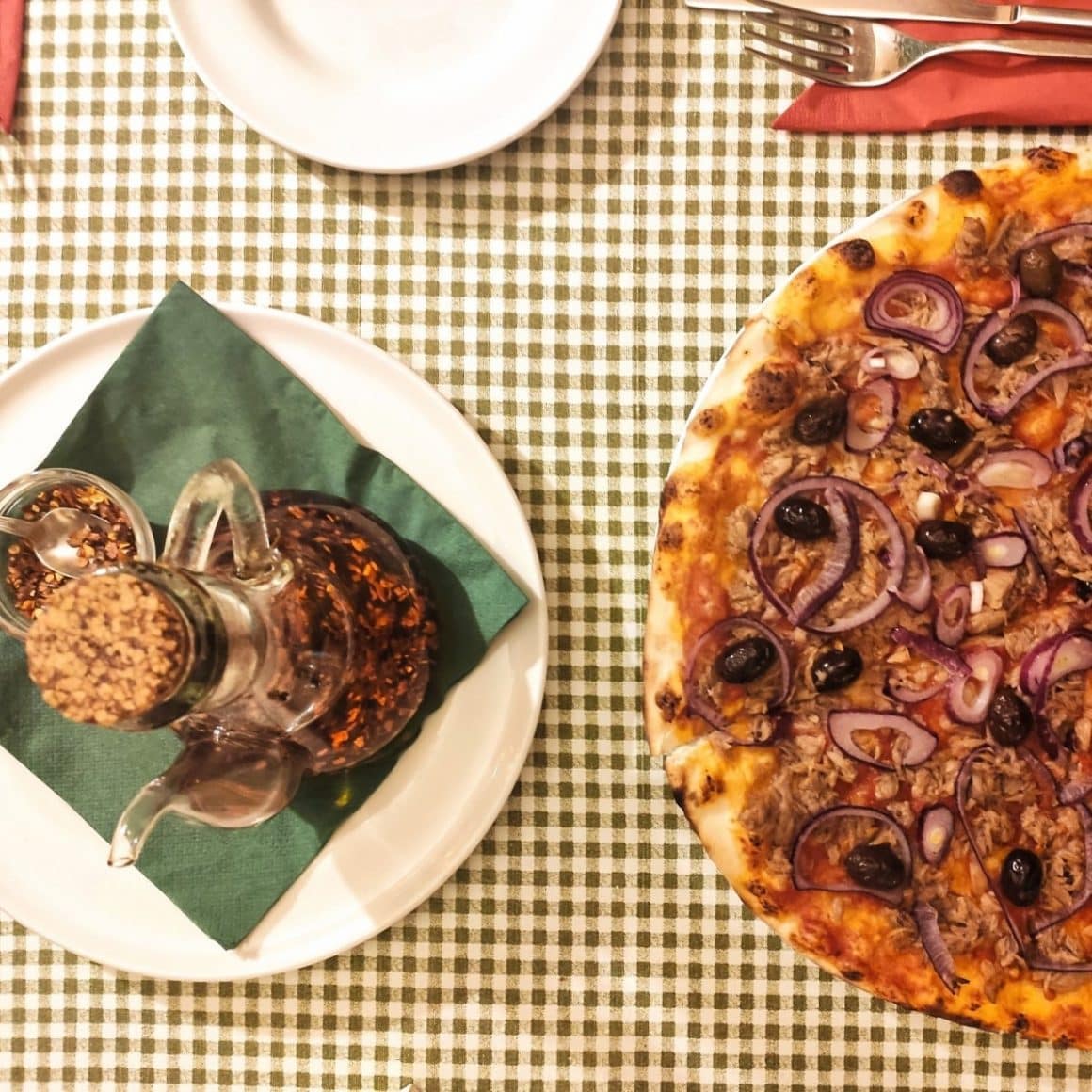 masa fotografiata de sus, cu o farfurie de pizza langa o oliviera