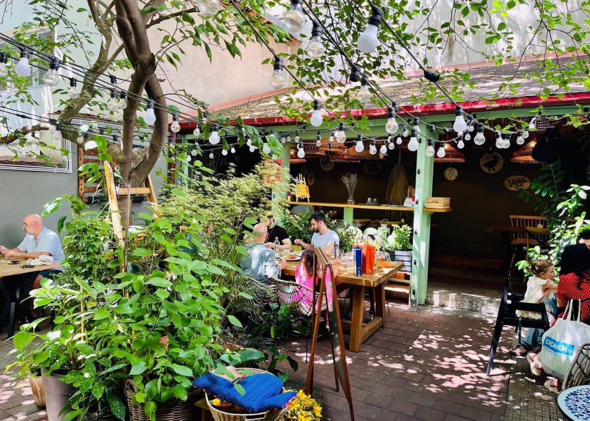 oaspeti iau masa afara, vara, pe terasa la Bacania Veche din Bucuresti