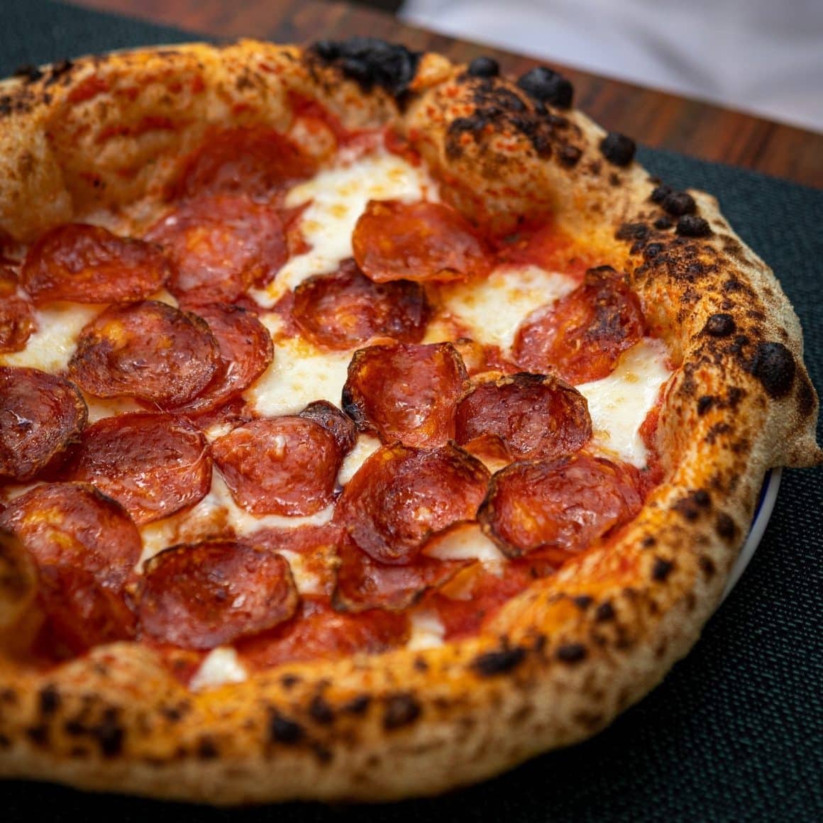 pizza cu blat rumen, Sos de roșii San Marzano, mozzarella Fior di Latte, salam Salsiccia Napoli Piccante, de la PizzaMania București