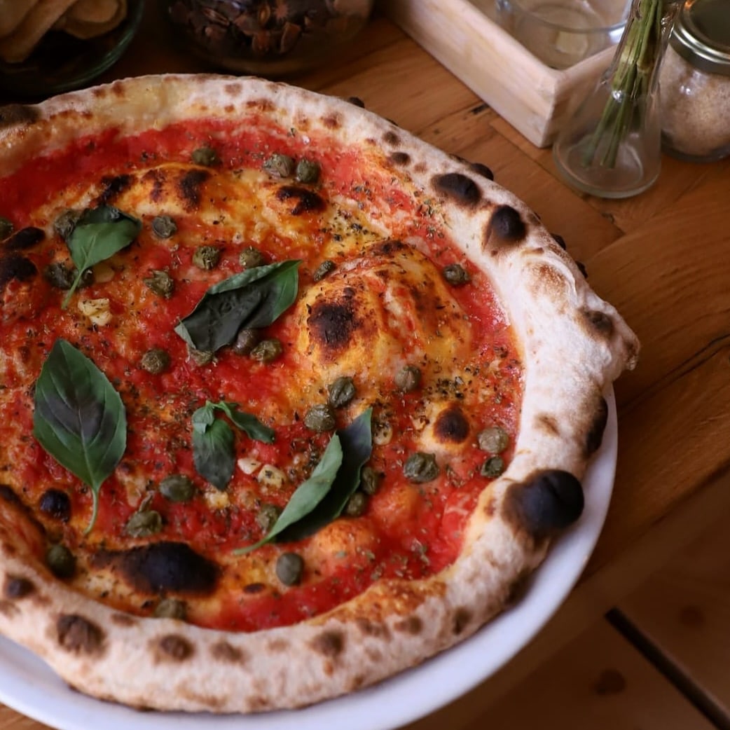 Pizza vegetariana, cu sos de roșii, capere, oregano uscat, usturoi, ulei de măsline presat la rece, busuioc.