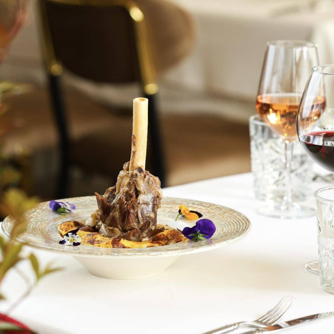 rasol de miel servit pe o farfurie la restaurant, alaturi de pahare de vin. 