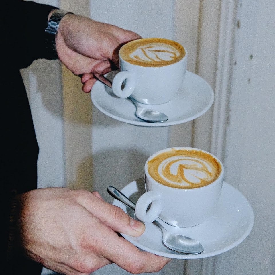 close up cu o persoana care duce in maini 2 cesti de cafea